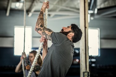Man using climbing rope at cross training gym