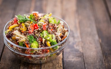 Quinoa and vegetable salad in a glass bowl on a wooden table