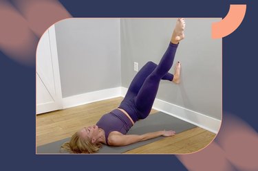 Person in a matching purple workout outfit doing a wall pilates workout on a mat