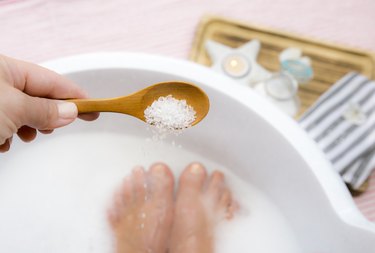 Adding Magnesium Chloride vitamin salt in foot bath water, solution. Magnesium grains in foot bath water are ideal for replenishing the body with this essential mineral, promoting overall wellbeing.