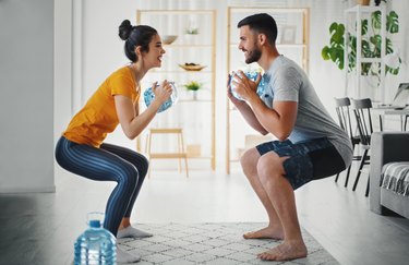 Couple working out at home with a jug of water