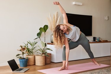woman with curly hair doing the triangle pose yoga hip opener as part of a yoga flow for tight hips