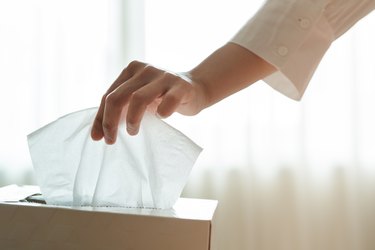 close view of a hand picking a tissue from the tissue box