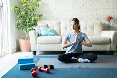 woman working out with a yoga block and dumbbells in her living room