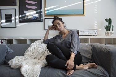 Portrait confident Latina woman relaxing on living room sofa