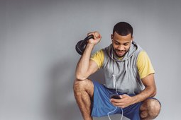 Man listening to workout music holding a kettlebell