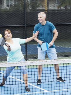 A man and woman playing pickleball on the same team