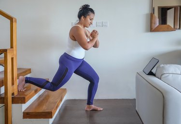 woman wearing purple leggings doing a stair glute workout at home