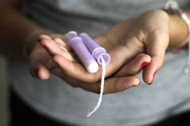 close view of two tampons in a person's hands, to represent pain when inserting a tampon